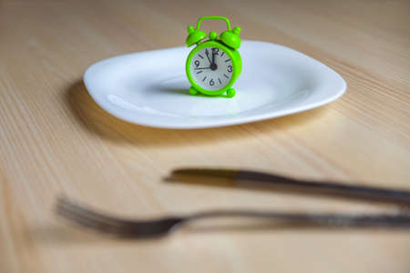 Alarm clock,empty plate and utensils on a wooden backgroundの写真素材