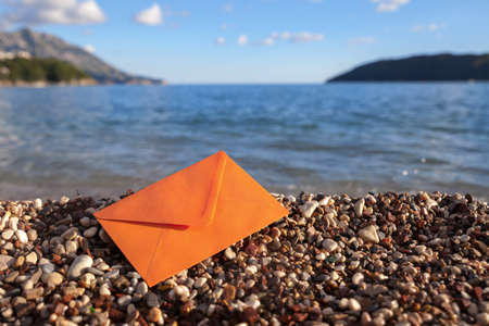One orange envelope on a gravel beachの写真素材
