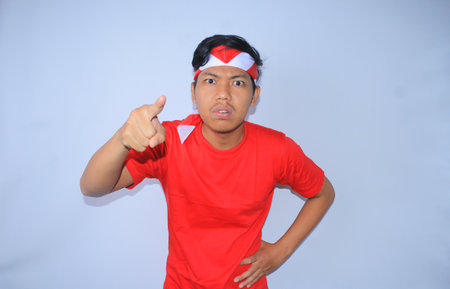 angry indonesian young man pointing his forefinger to camera wearing red t shirt and headband in indonesia independence dayの写真素材