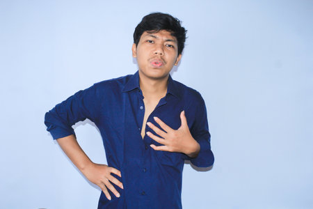 over time asian young man office worker is tired with hand on waist and hold his chest get heart diseases symptomsの写真素材