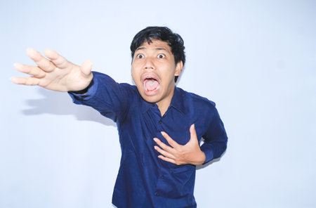 heart attacked asian man office worker screaming and touch his chest with gesture reaching out for help suffering from heart pain, wear navy shirtの写真素材