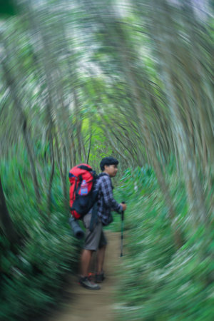 defocused  of young adult man walking alone hiking in trekking path of arjuno mountain carrying carrier with radial motion, side viewの写真素材