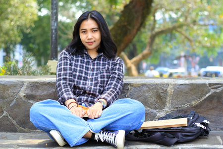 happy young asian woman college student with smiling face enjoy read a book for exam in the parkの写真素材