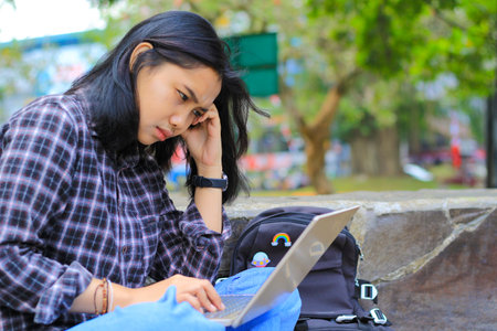 exhausted and stressed asian woman student working using laptop and study with text books in...