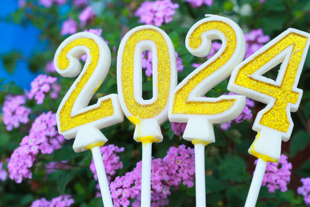 golden and glittering candle number 2024 over pink flower with grean leave, 20 24 new year eve background conceptの写真素材