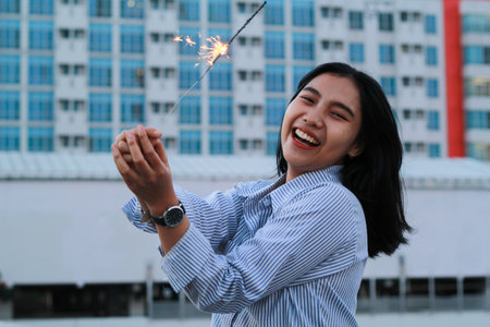 happy asian young business woman holding sparklers to celebrate new year eve standing in outdoor...