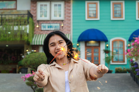 happy young asian woman holding sparkler celebrating new year eve in vintage house yard, outdoor gardenの写真素材