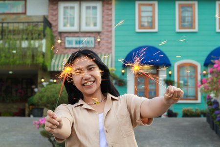 happy young asian woman holding sparkler celebrating new year eve in vintage house yard, outdoor gardenの写真素材