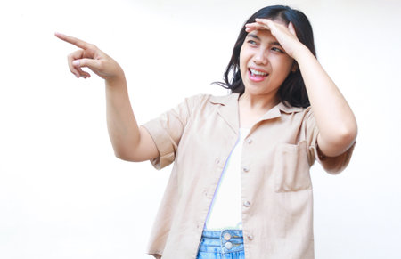 excited asian woman pointing finger showing presenting gesture wearing casual clothes isolated on white backgroundの写真素材