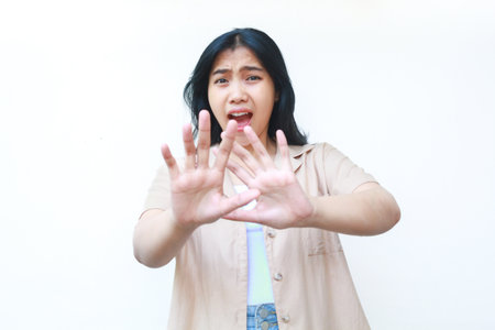 shocked asian woman covering her mouth wearing casual brown clothes isolated on white backgroundの写真素材