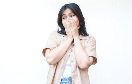 shocked asian woman covering her mouth wearing casual brown clothes isolated on white backgroundの写真素材