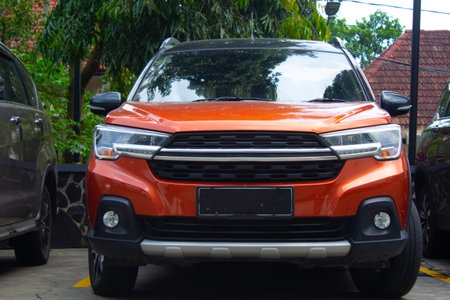 front view of orange color suv cars 4wd for adventure and off road parked under green trees in...