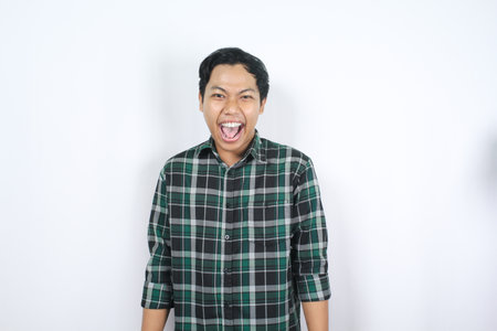 isolated excited asian man wearing checkered shirt screaming to announce with looking at cameraの写真素材