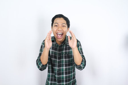 handsome attractive asian young man standing over isolated background wearing checkered shirt...