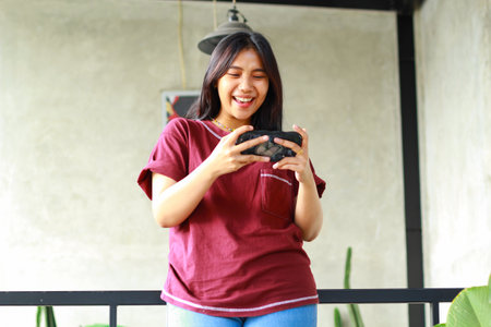 asian woman excited playing game online using smartphone standing around railingの写真素材