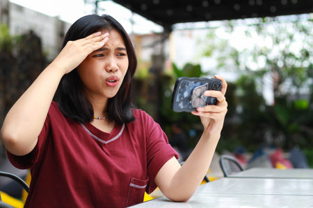 asian woman stressed playing online game using smartphone while sitting in cafe