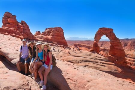 Smiling happy family on vacation hiking trip. People relaxing  on top of  mountain next to Delicate...