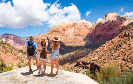Family hiking on vacation, relaxing on top of the mountain, looking at beautiful  mountains scenery.  Zion National Park, Utah, USAの写真素材