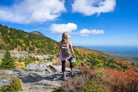 Hiker girl standing on top of mounenjoying scenic fall view. Woman on hiking trip relaxing and  looking at beautiful autumn mountain scenery. Grandfather Mountain State Park,  North Carolina, USA.の写真素材