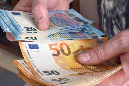Man hand counting 50 euro and 20 euro banknotes.
