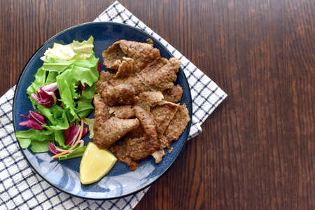 Turkish lamb doner kebab with vegetable salad and lemon on a blue plate. Copy space is on the right side. Food from above concept. Flat lay top view photo.の写真素材
