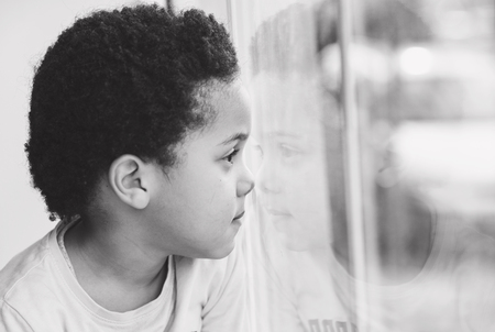 cute Afro american boy looking through the windowの写真素材