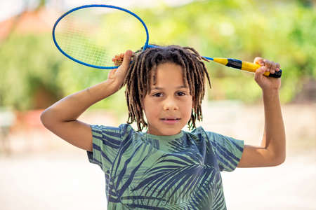 Closeup cute little black American boy holding a badminton racket, Outdoorの写真素材