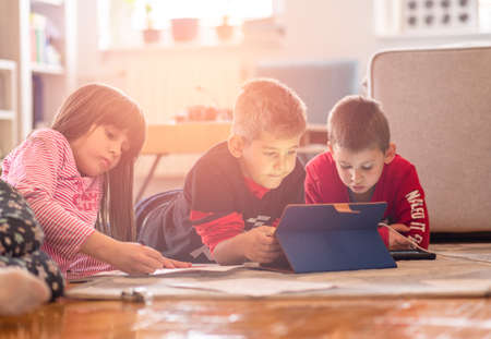 Kids playing with laptop computer at homeの写真素材
