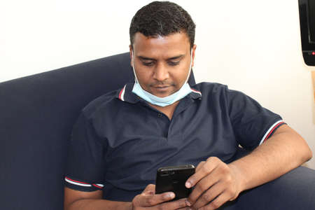 young asian man using cellphone in living roomの写真素材