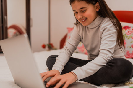 A happy teenager girl using a laptop while comfortable sitting on sofa at home.の写真素材