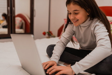 A happy teenager girl using a laptop while comfortable sitting on sofa at home.の写真素材