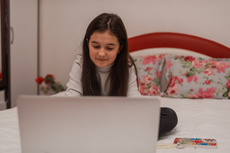 A happy teenager girl using a laptop while comfortable sitting on sofa at home. High quality photo