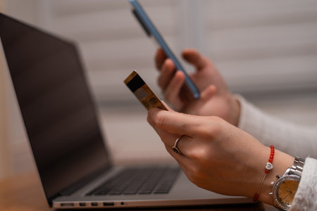 Female hands using mobile phone and holding credit card checking balance or making money transfer....