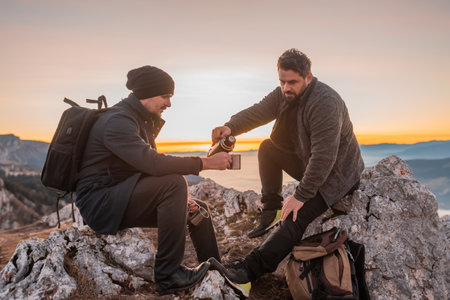 Two happy friends tourists drinking a cup of coffee or tea during the hiking on the mountain adventure travel.の写真素材