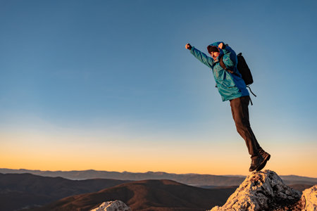A happy man traveler jumping on the mountain top, adventure travel.