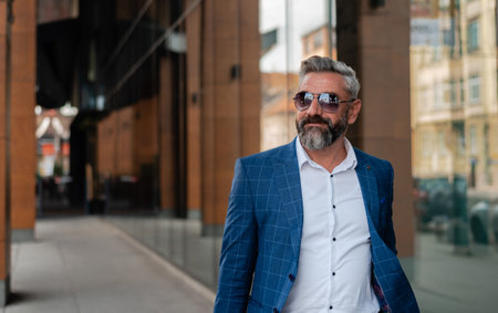 A mature business man is walking through the city street near the office building.の写真素材