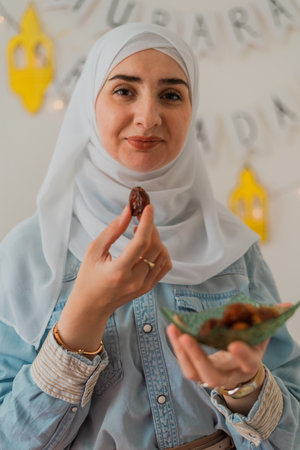 A happy Muslim woman eating dates for iftar to break fast during the holy month Ramadan concept of passing sharing food.の写真素材