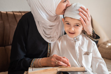 A happy Muslim family mother with lovely child son reading a holy book Quran at the home.の写真素材