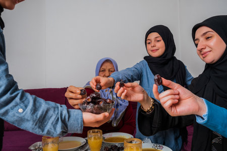 Happy Muslim family having iftar dinner at home during Ramadan dining table eating dates to break fast.の写真素材