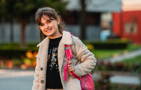 A portrait of a happy girl student with school backpack outside.