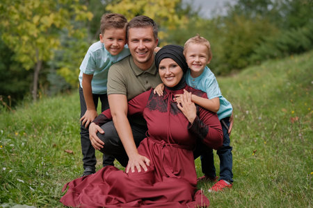 Portrait of a happy Muslim family, young mother and father with two child in the summer park,...