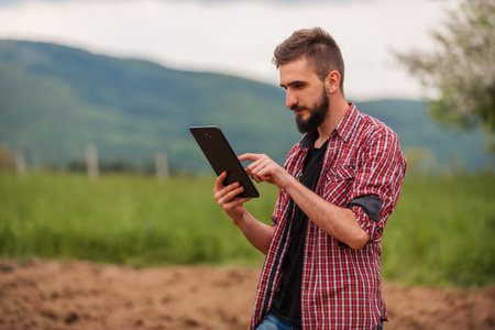 Male farmer plantation checking quality by tablet agriculture modern technology concept smart farming agronomist checking soil quality on the field.の写真素材