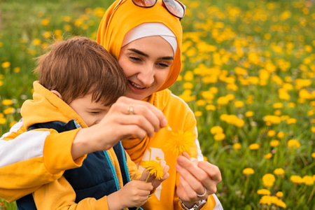 Happy Muslim family having a fun mother and child boy playing with dandelion in the flowering spring field.の写真素材