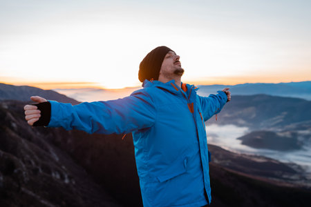 A carefree relaxing man deep breathing with arms outstretched and eyes closed in nature.の写真素材