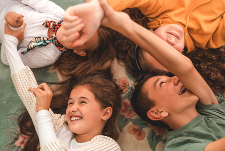 Happy group of children friends lying on the floor in a circle and having a fun, top view.の写真素材