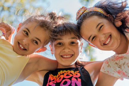 Close up face of happy children embracing each other and smiling at camera, group of joyful kids playing together outside.の写真素材
