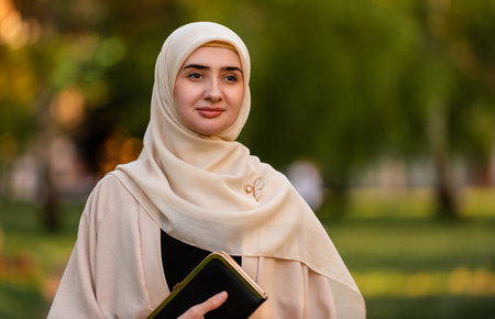 Portrait of a young happy Muslim woman in hijab outside.