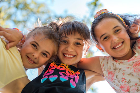 Happy children embracing each other having fun and smiling at the camera with a sky background, a...