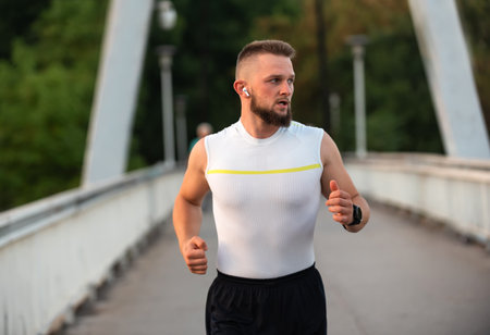 Young athletic man running or jogging on a city bridge, active healthy lifestyle.の写真素材