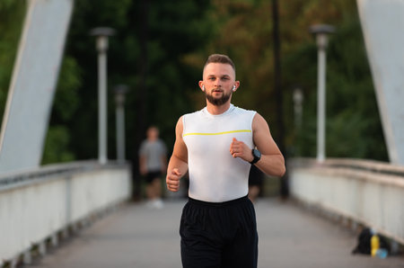 Young athletic man running or jogging on a city bridge, active healthy lifestyle.の写真素材